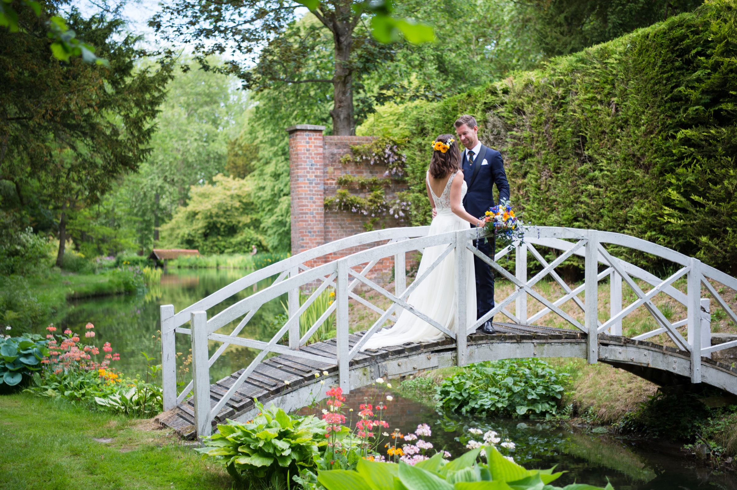 A bride and groom on a bridge in the gardens of Adwell House in Oxfordshire